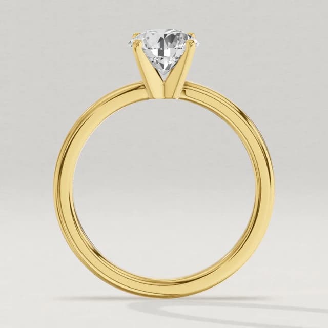 Profile view through the finger hole of a yellow gold four-claw solitaire engagement ring with a 1 carat round diamond, showing how high the stone sits above the band, a 3D render at the same scale as the 1.5, 2 and 3 carat rings beside it