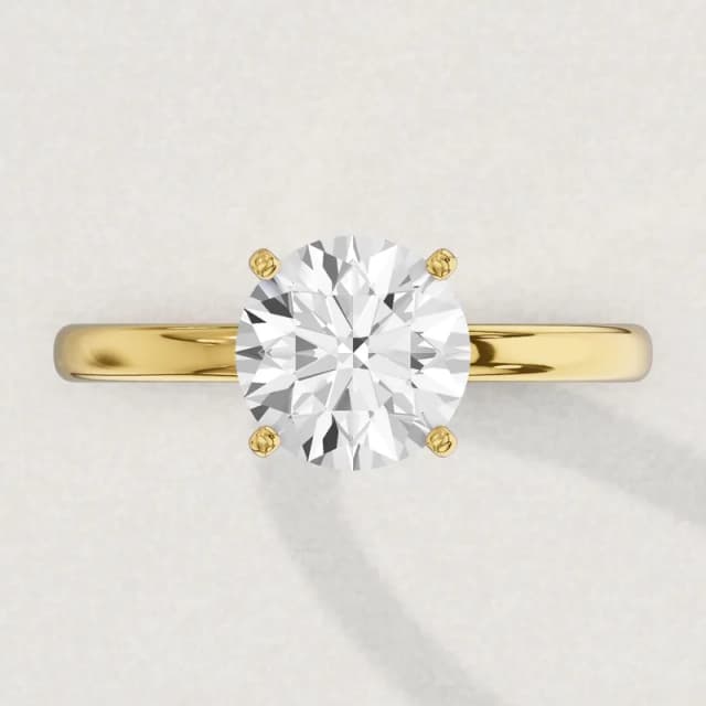Face-up view of a yellow gold four-claw solitaire engagement ring on a 2 mm band with a 2 carat round diamond 8.1 mm across, a 3D render drawn to the same scale as the other face-up rings on this page