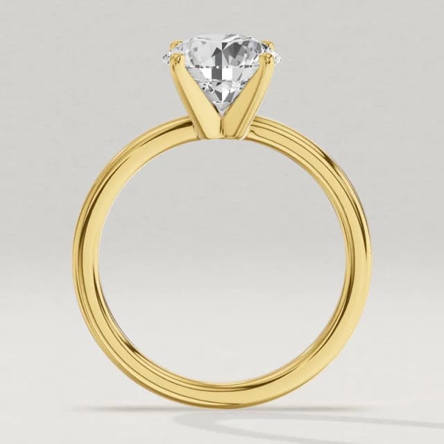 Profile view through the finger hole of the same yellow gold four-claw solitaire with a 2 carat round diamond, its head a little taller and wider, a 3D render at the same scale as the 1, 1.5 and 3 carat rings beside it