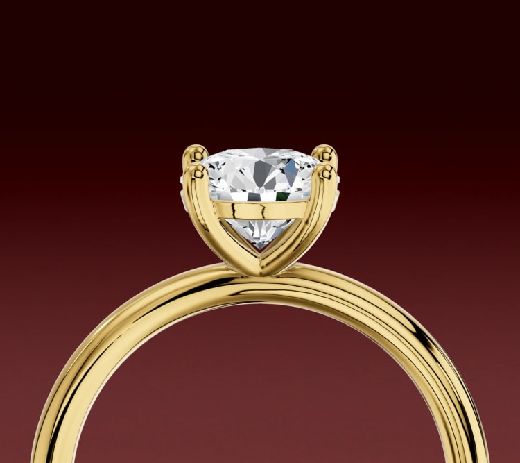 Side view of a non-cathedral round diamond solitaire, with the head sitting directly on a plain yellow gold band, by Lily Dia Jewellery