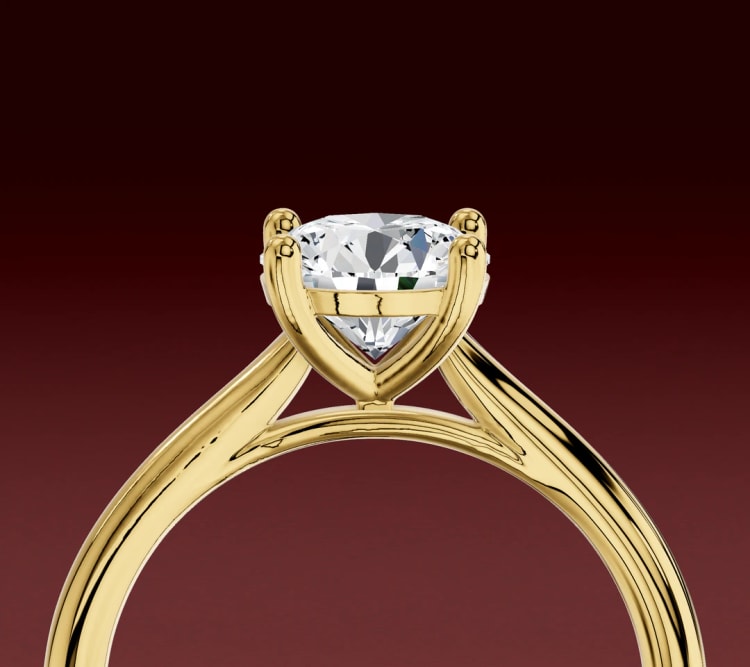 Side view of a cathedral round diamond solitaire, with yellow gold shoulders arching up to the head, by Lily Dia Jewellery