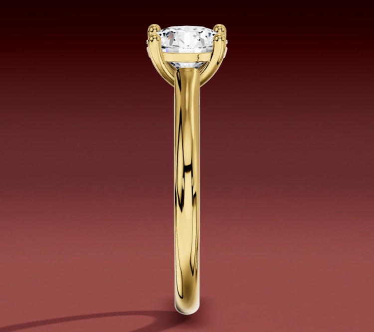 Cathedral solitaire seen edge-on, showing the head above the narrow profile of the yellow gold band, by Lily Dia Jewellery