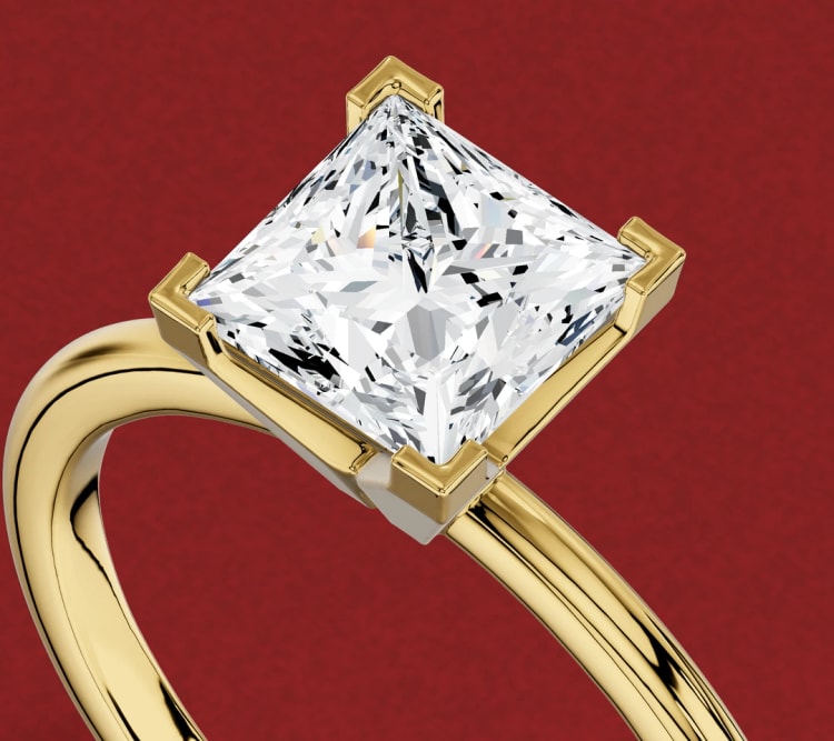 Princess cut diamond engagement ring in yellow gold with V-shaped corner claws, seen at an angle, by Lily Dia Jewellery