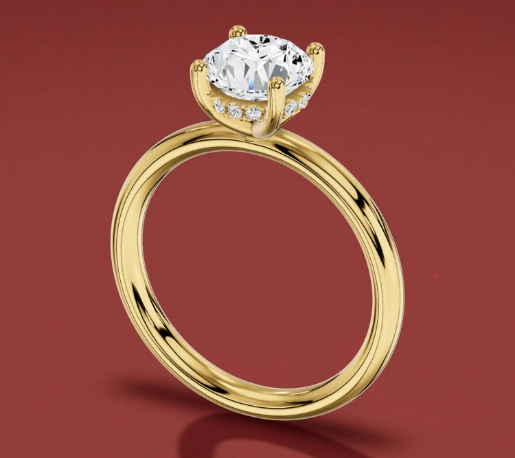 Hidden halo engagement ring in yellow gold, seen at an angle with small diamonds under the centre stone, by Lily Dia Jewellery