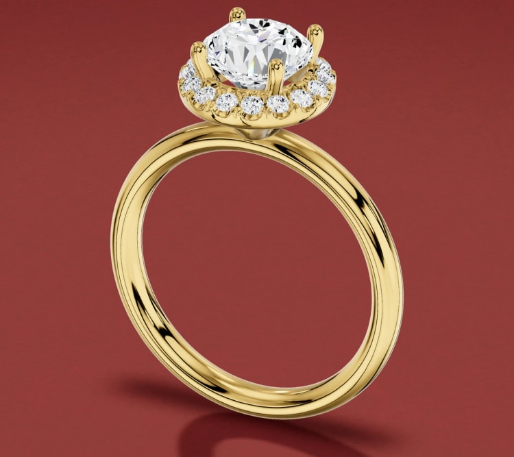 Halo engagement ring in yellow gold, seen at an angle with the halo framing the round diamond, by Lily Dia Jewellery