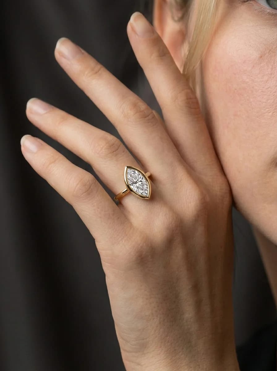 A marquise cut diamond bezel-set engagement ring worn on the hand, the bezel wrapping and protecting the pointed tips, a marquise cut diamond shape education guide by Lily Dia Jewellery