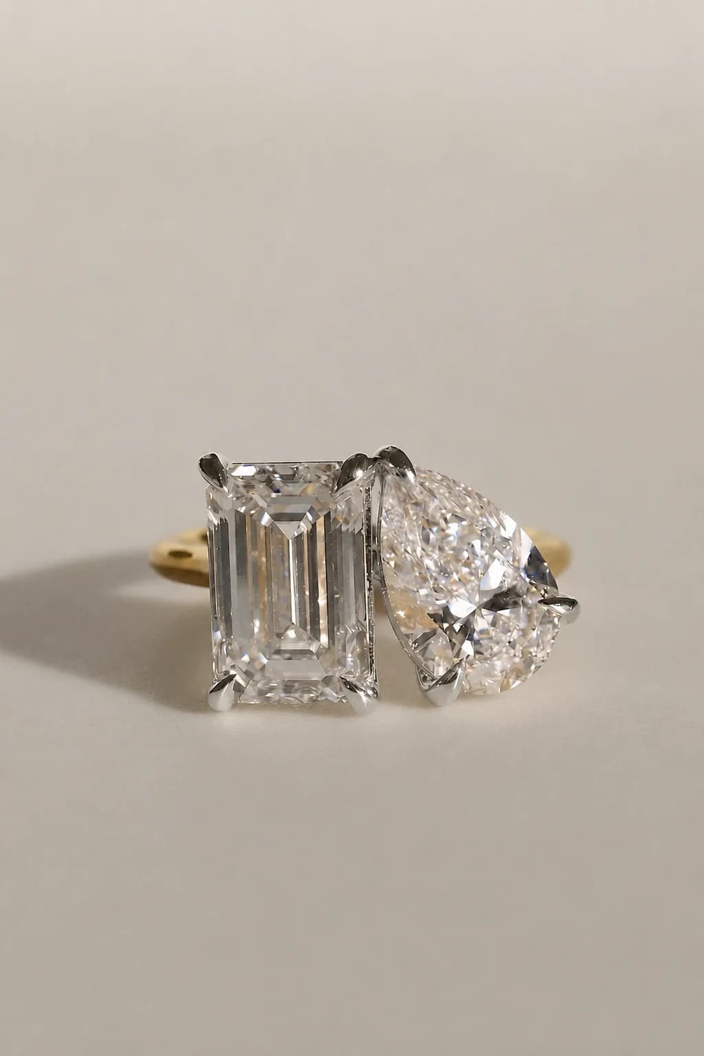A pear shaped diamond and an emerald cut diamond set together in a yellow gold toi et moi engagement ring, a pear shaped diamond shape education guide by Lily Dia Jewellery