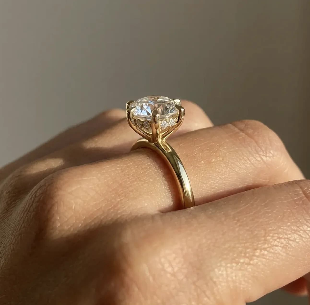 A round brilliant solitaire engagement ring in yellow gold shown in profile on the hand, a solitaire engagement ring style guide by Lily Dia Jewellery