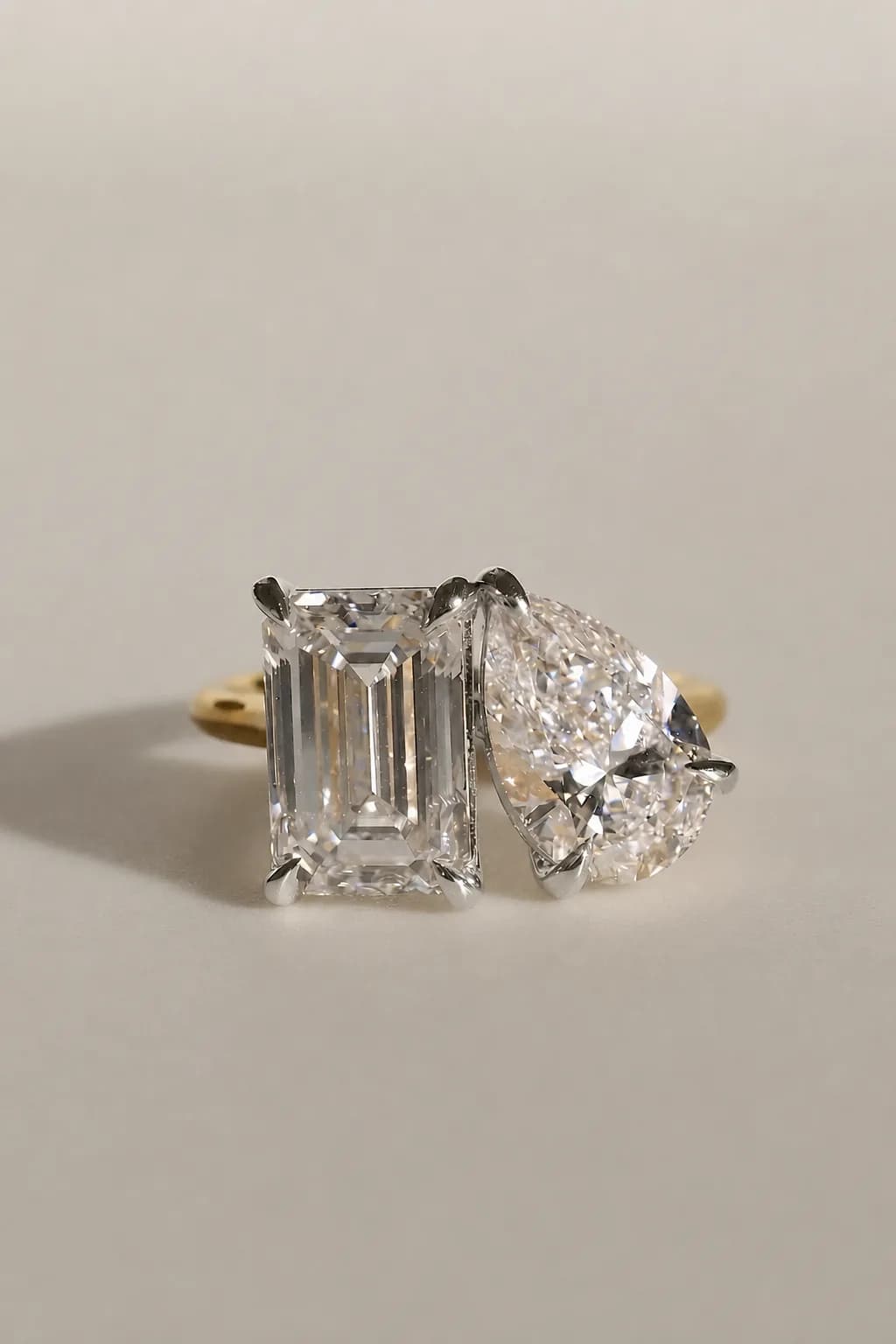 An emerald cut diamond set beside a pear cut diamond on a yellow gold toi et moi engagement ring, a toi et moi engagement ring style guide by Lily Dia Jewellery