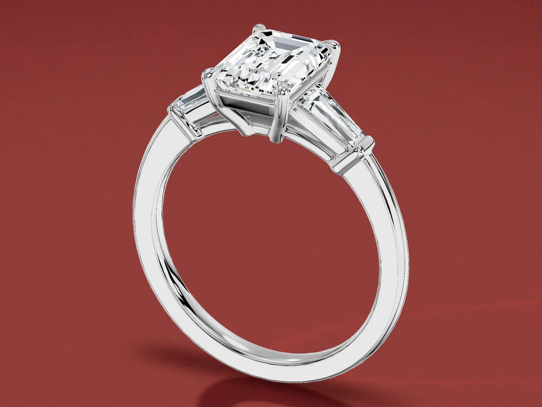 3D render of a white gold ring with an emerald cut centre stone between two tapered baguettes.