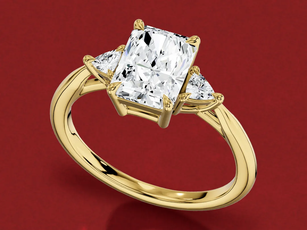 3D render of a yellow gold ring with a radiant-cut centre diamond and a trillion-cut diamond on each side.