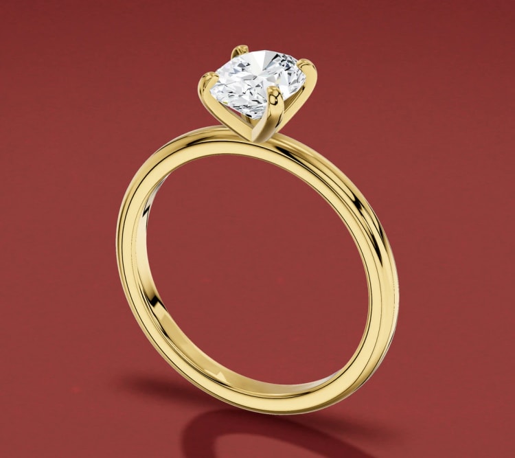 North-south oval diamond four-claw engagement ring in yellow gold, seen at an angle, by Lily Dia Jewellery