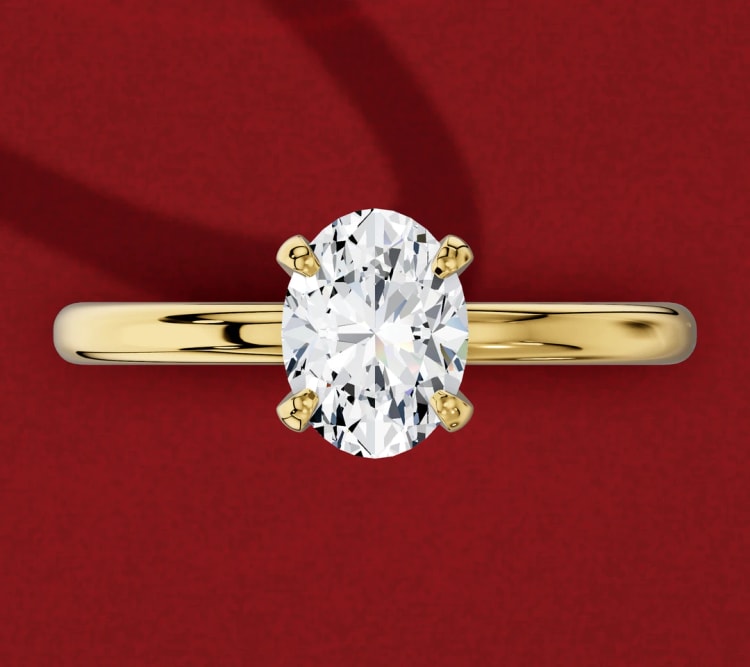 North-south oval diamond engagement ring with four claws on a plain yellow gold band, seen from above, by Lily Dia Jewellery
