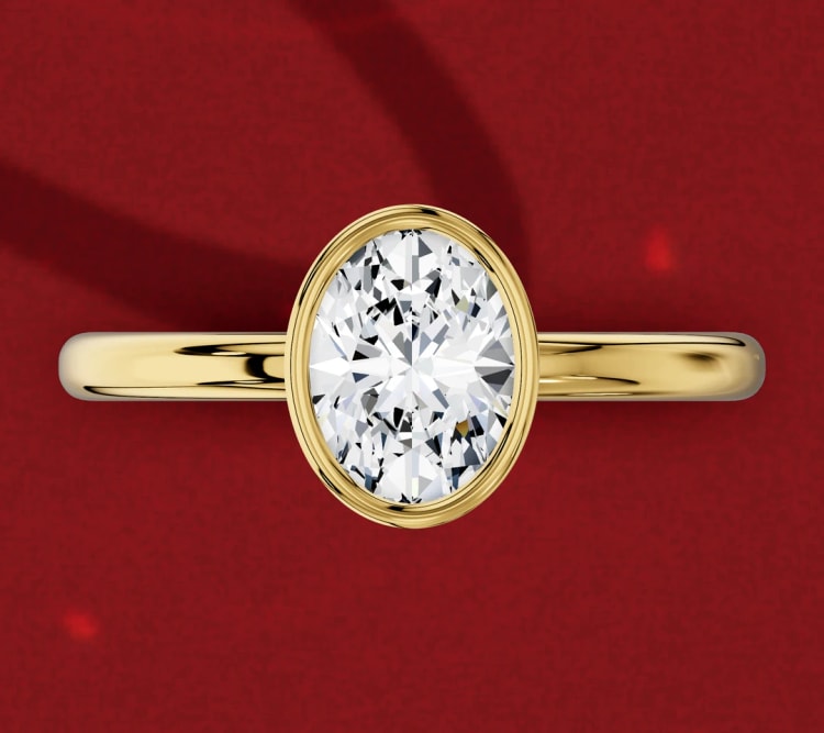 North-south oval diamond in a yellow gold bezel setting on a plain band, seen from above, by Lily Dia Jewellery