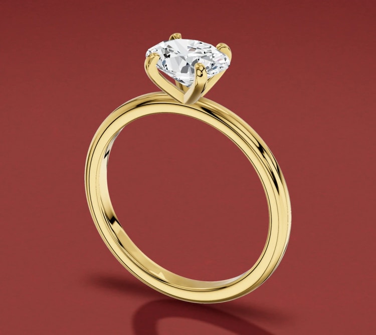 East-west oval diamond four-claw engagement ring in yellow gold, seen at an angle, by Lily Dia Jewellery
