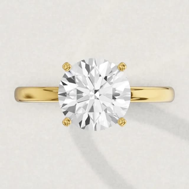 Face-up view of a yellow gold four-claw solitaire engagement ring on a 2 mm band with a 3 carat round diamond 9.3 mm across, a 3D render drawn to the same scale as the other face-up rings on this page