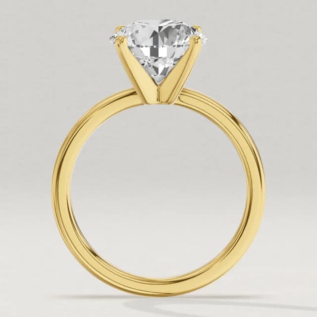 Profile view through the finger hole of the same yellow gold four-claw solitaire with a 3 carat round diamond, the tallest head of the four, a 3D render at the same scale as the 1, 1.5 and 2 carat rings beside it