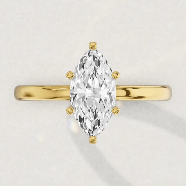 Face-up view of a yellow gold claw-set solitaire engagement ring on a 2 mm band with a marquise diamond the size of our 2 carat marquise stones, about 13.2 by 6.6 mm, a 3D render drawn to the same scale as the other face-up rings on this page