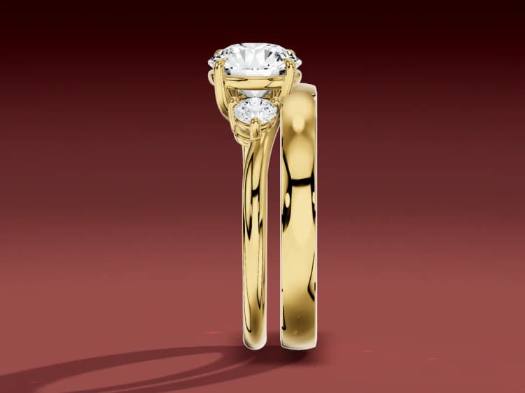 3D render of a three-stone ring and a straight wedding band seen edge-on, the band stopped by the side stones with a gap between the bands