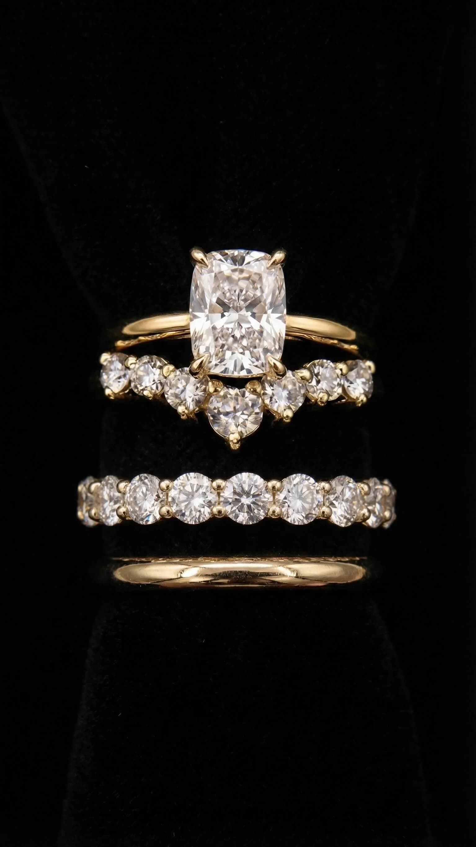 Cushion-cut diamond engagement ring with two diamond wedding bands on black velvet